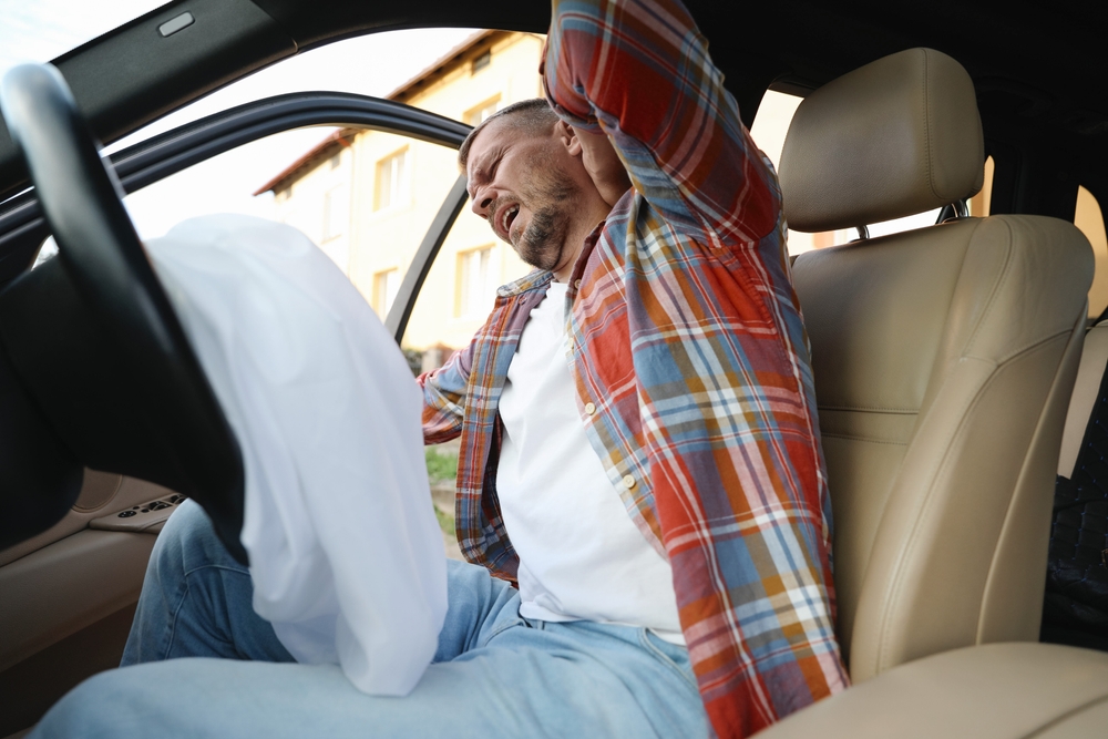 A driver holds his neck in pain after a car accident, representing whiplash and injury symptoms that may require chiropractic treatment - boca raton auto accident chiropractor