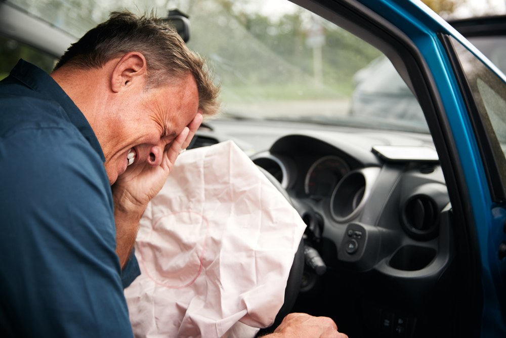 A driver holds his face after an auto accident with airbag deployment, representing injuries that may require chiropractic evaluation and recovery care - Auto Accident Chiropractor in Parkland