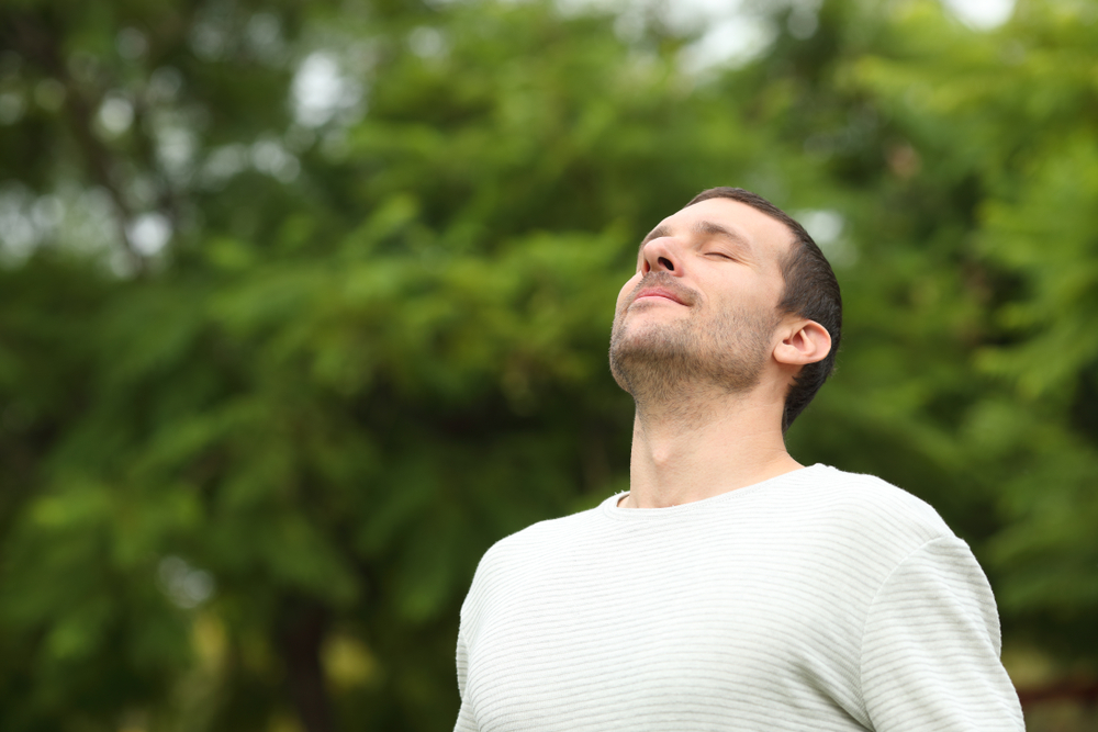 A man practices deep breathing outdoors to support relaxation, healing, and wellness during recovery